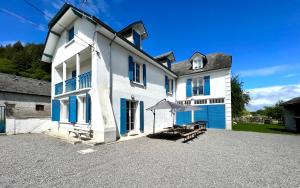 een groot wit huis met een tafel en een paraplu bij Refuge de luxe pour les amoureux de la montagne in Pouzac