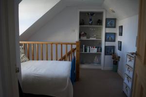 a bedroom with a staircase with a bed and shelves at Coach House. Falcon Mews in Bude
