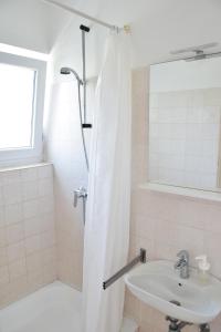 La salle de bains blanche est pourvue d'une douche et d'un lavabo. dans l'établissement Guest house Tina, à Rab