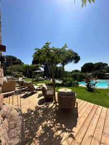a wooden deck with chairs and an umbrella and the ocean at Hôtel Ambassador Palombaggia in Porto-Vecchio