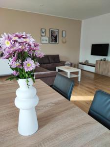 a white vase with purple flowers in a living room at Ferienwohnung Magel in Waldsolms