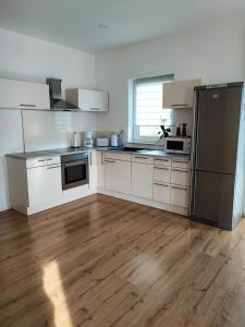 a kitchen with white appliances and a wooden floor at Ferienwohnung Magel in Waldsolms