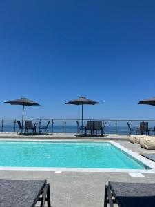una piscina con tavoli e ombrelloni e l'oceano di MELIKIRON LUXURY APARTMENTS a Ayios Nikitas
