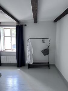 ein weißes Zimmer mit einem Fenster und einem weißen Hemd auf einem Kleiderständer in der Unterkunft Maison le Bonheur - 12P Met Zwembad FR Vakantiehuis in Magny-lès-Jussey
