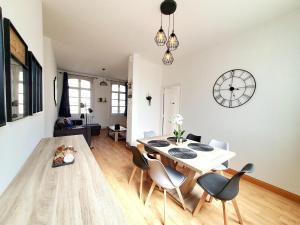 een woonkamer met een tafel en stoelen en een klok bij Le Carillon - hypercentre - WIFI in Douai