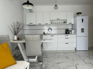 a white kitchen with a table and a refrigerator at Apartments Jurić in Brodarica