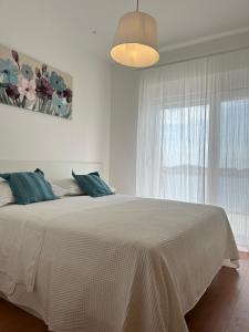 a white bedroom with a large bed with a window at Apartments Jurić in Brodarica