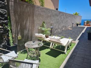 un patio con mesa y sillas en el césped en Vivienda vacacional Vistamar, en Santa Cruz de Tenerife