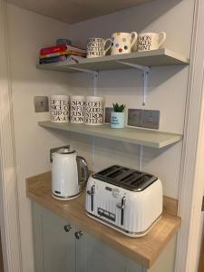 a kitchen shelf with a toaster and tea pots at Harbour quay in Wick