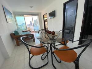 - une table et des chaises en verre dans le salon dans l'établissement Apartamento Excalibur 11B junto al mar, à Gaira