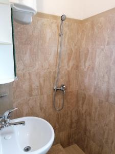 La salle de bains est pourvue d'une douche et d'un lavabo blanc. dans l'établissement Роден Край Homeland, à Sopot