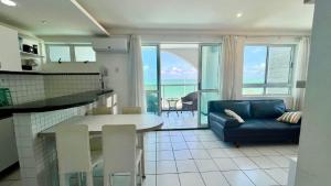 eine Küche und ein Wohnzimmer mit einem Sofa und einem Tisch in der Unterkunft Beira Mar 226 Praia - NBI - Ponta Negra Beach - Pe na areia e ultimo andar e Vista x Mar in Natal