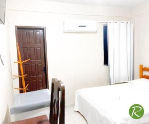 ein weißes Zimmer mit einem Bett und einer Tür in der Unterkunft Hotel Rio in Tucuruí