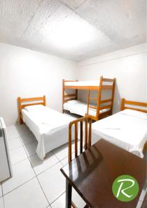 2 camas en una habitación con mesa y sillas en Hotel Rio, en Tucuruí