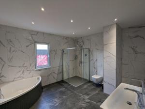 a bathroom with a tub and a shower and a sink at S'bahnhöfle Apartments in Ringsheim