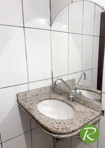 a bathroom sink with a granite counter top at Hotel Rio in Tucuruí