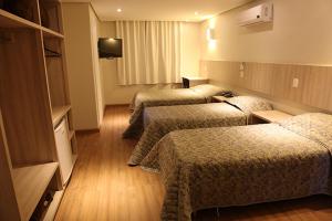 um quarto de hotel com três camas e uma televisão em Golden Hotel em Chapecó