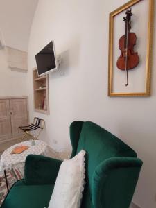 a living room with a green couch and a violin on the wall at ROSSINI GUEST HOUSE in Martina Franca