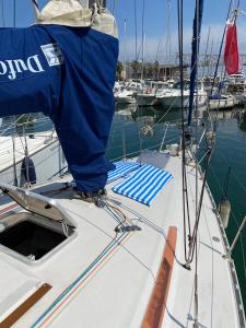 a white boat with a blue tarp on the bow at Acogedor velero en el Forum in Barcelona