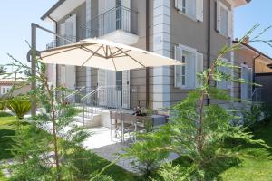 une terrasse avec un parasol en face d'un bâtiment dans l'établissement Lido Luxury Villas, à Lido di Camaiore