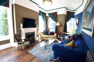 a living room with a blue couch and a fireplace at The Huntress Suite in Buxton