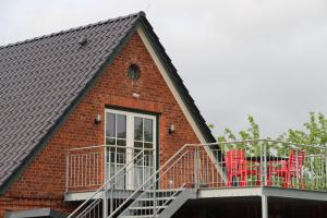 Cette maison en briques rouges dispose d'un balcon avec des chaises rouges. dans l'établissement Ferienwohnung Fritz, à Jork