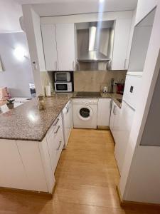 a kitchen with white cabinets and a washer and dryer at RESIDENCIAL MICHELANGELO in Salou