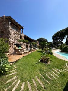 a house with a grassy yard next to a pool at Hôtel Ambassador Palombaggia in Porto-Vecchio