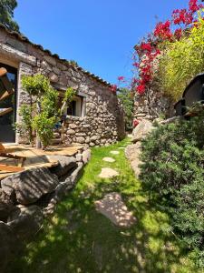 a garden with a stone building and a stone path at Hôtel Ambassador Palombaggia in Porto-Vecchio