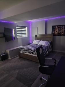 a bedroom with a bed and a chair and purple lights at Modern Apartment London Ontario in London