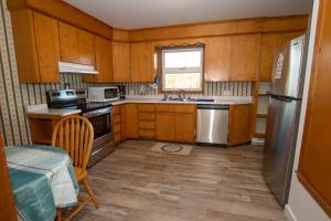 a kitchen with wooden cabinets and a stainless steel refrigerator at La Maison Mavillette The Mavillette house 2BD in Mavillette