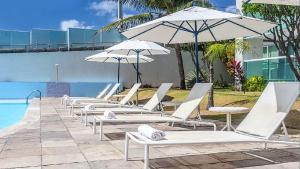 eine Reihe von Liegestühlen und Sonnenschirmen neben einem Pool in der Unterkunft Beira Mar 226 Praia - NBI - Ponta Negra Beach - Pe na areia e ultimo andar e Vista x Mar in Natal
