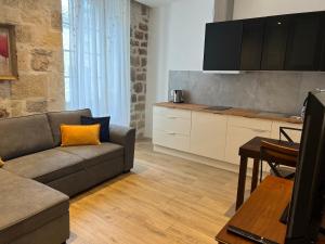 ein Wohnzimmer mit einem Sofa und einer Küche in der Unterkunft Le Beffroi Hôtel & Apart in Tournon-dʼAgenais