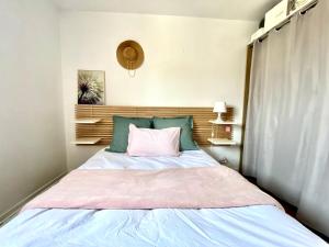 a bedroom with a bed with a pink pillow at Le cocon chaleureux in Vannes