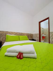 HOTEL LA GAITANA HEROINA INDIGENA في سان أوغستين: سرير أخضر مع مناشف بيضاء ومرآة