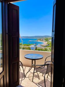 a balcony with a table and chairs and a view of the ocean at Vasilikos Apartments in Paralia Agias Foteinis