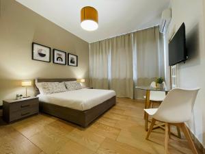 a bedroom with a bed and a table and a television at Le Dimore del Corso in Catania