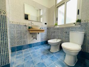 a blue tiled bathroom with a toilet and a sink at Le Dimore del Corso in Catania