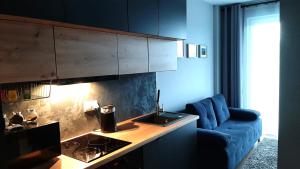 a living room with a blue couch and a kitchen at Apartament Wawa in Warsaw