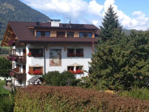 a white house with red flowers in the windows at Residence Magdalena in Ortisei