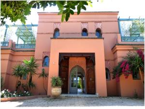 une maison rose avec une arche devant elle dans l'établissement Villa Palmeraie, à Marrakech