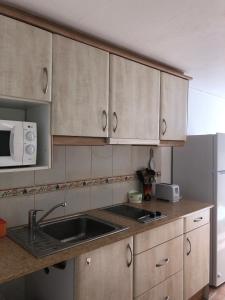 cocina con armarios blancos, fregadero y nevera en Apart Calan Forcat Menorca, en Cala en Forcat