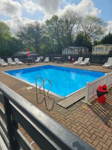 a large blue swimming pool with chairs and a table at Static 19 in Llandysul