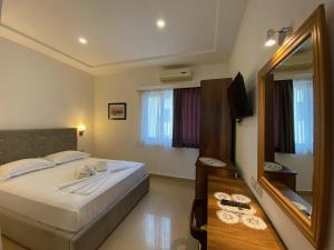 a bedroom with a large bed and a mirror at Hotel Republika Berat in Berat