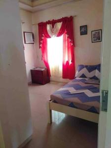um quarto com uma cama e uma janela com cortinas vermelhas em Room In Lobo Triple N Homestay 2nd N 