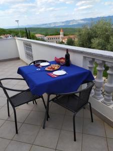 une table avec une assiette de nourriture sur un balcon dans l'établissement Apartmani Danica, à Vrbnik