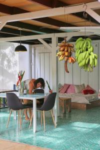 a woman sitting at a table in a room with bananas at Casa BOHÖ in Puerto Viejo