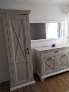 La salle de bains est pourvue d'une armoire blanche et d'un miroir. dans l'établissement Apartmani Danica, à Vrbnik