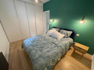 een slaapkamer met een bed en een groene muur bij Appart 1 chambre neuf confort in Rouen