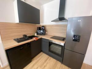 cocina con nevera de acero inoxidable y fregadero en Appart 1 chambre neuf confort, en Rouen